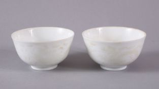 A PAIR OF CHINESE WHITE MONOCHROME GLAZED PORCELAIN TEA BOWLS - the body decorated with scenes of