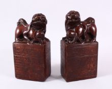 A PAIR OF UNUSUAL TERRACOTTA / POTTERY LION DOG SEAL / DESK WEIGHTS, each dog modeled with their paw
