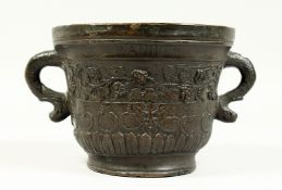 A TWO HANDLED BRONZE MORTAR, with serpent handles, the body with masks and fruiting vines. Dated