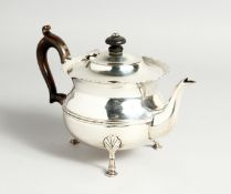 A CIRCUALR SILVER TEA POT with waved rim and wooden handles. London 1902, maker C.B. Weighs 14oz.