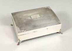 AN ENGINE TURNED SILVER TABLE CIGARETTE BOX with cedar wood liner on four claw and ball feet. 6.5ins