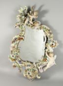 A LARGE PORCELAIN MIRROR in the MEISSEN style, encrusted with flowers, cherubs and scrolls. 32ins