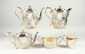 A VICTORIAN SILVER FIVE PIECE TEA SET a with scroll and repousse decoration. Initialed A. Comprising