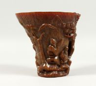 A LARGE CHINESE LIBATION CUP carved with figures, probably resin. Signed, 5ins high.