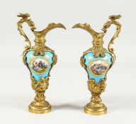 A GOOD PAIR OF SILVER GILT BRONZE AND PORCELAIN EWERS with a blue ground and vignettes of figures