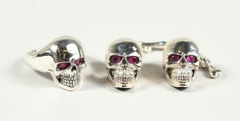 A PAIR OF SILVER SKULL CUFF LINKS AND RING, with ruby eyes.