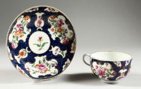 A WORCESTER FINE BLUE SCALE TEACUP AND SAUCER,robustly painted with English garden flowers in gilt