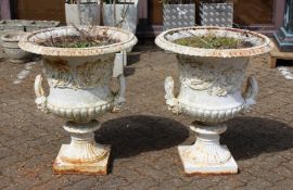 A GOOD PAIR OF VICTORIAN WHITE PAINTED CAST IRON CAMPAGA VASES with mask handles on square bases.