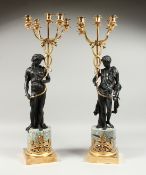 A VERY GOOD PAIR OF BRONZE CLASSICAL CANDELABRA on classical figures holding five candles, on a