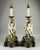A LARGE PAIR OF MAJOLICA POTTERY LAMPS,with three cupids around a tree.