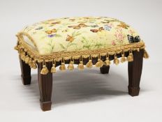 A SMALL FOOTSTOOL UPHOLSTERED with a butterfly tapestry material. 1ft 5ins long x 1ft high.