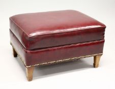 A RED LEATHER UPHOLSTERED FOOTSTOOL, on tapering square legs. 2ft 2ins x 1ft 3ins high.