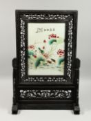 A CHINESE PORCELAIN PLAQUE painted with peonies, in a wooden stand.