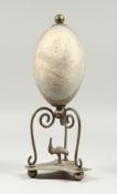 AN AUSTRALIAN EMU EGG with plated mount and wooden base, etched with an eagle. Egg 5ins.