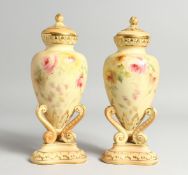 A PAIR OF GRAINGER &CO. ROYAL WORCESTER BLUSH IVORY URNS AND COVERS, painted with flowers on