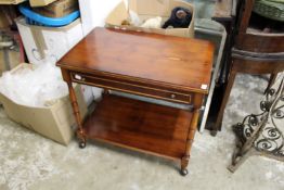 A yew wood two tier single drawer trolley.