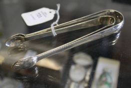 Two silver sugar tongs with bright cut decoration.