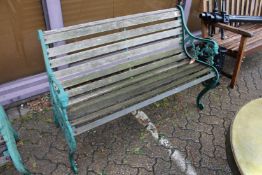 A garden bench with green painted cast metal ends.