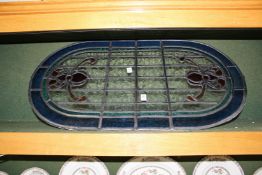 An oval leaded light stained glass window panel.