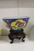A Chinese circular porcelain bowl painted with panels of flowers on a hardwood stand.