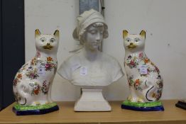 A pair of pottery cats and a Parian style bust of a young girl.