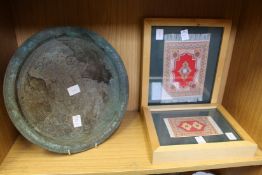 An eastern metal tray and two framed miniature Persian rugs.