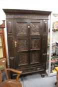 A Jacobean revival oak hanging cupboard with panelled door and single drawer, all with carved