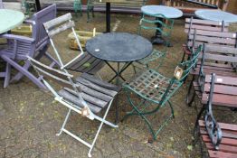 A small metal folding table and two pairs of wrought iron chairs.
