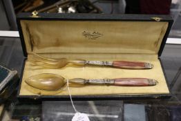 A cased set of salad servers possibly rhino horn.