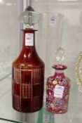 A ruby tinted cut glass decanter and stopper together with a floral decorated cranberry glass