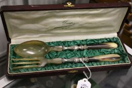 A cased set of salad servers, possible rhino horn.