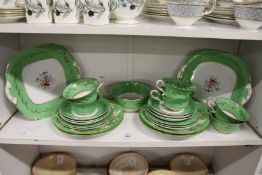 A quantity of floral decorated tea ware with green ground borders and gilded decoration.