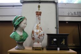 A bust of a young girl a pottery lamp and a painted cabinet.