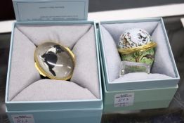 A Halcyon Days egg shaped enamel box and an oval box decorated with a cat.