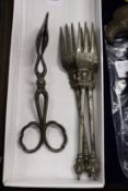 Three ornate forks and serving tongs.