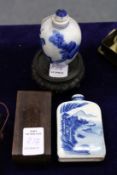 Two Chinese blue and white porcelain snuff bottles with associated wooden stands.