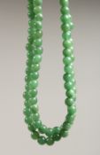 A STRING OF JADE BEADS 24ins long.