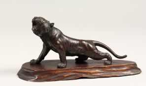 A SMALL JAPANESE BRONZE TIGER on a wooden base 5ins long
