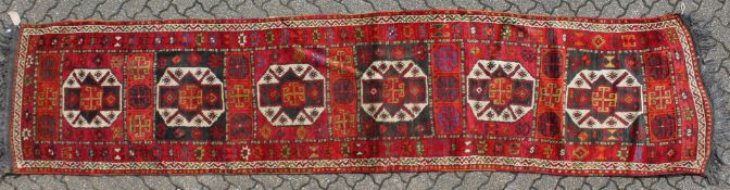 A LONG PERSIAN RUNNER with six main medallions 14ft long x 3ft 3ins wide