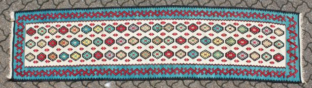 A KELIM RUNNER with three rows of twenty-two medallions. 9ft long x 2ft 3ins wide.