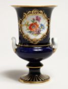 A SMALL MEISSEN TWO HANDLED URN on a blue ground painted with a panel of flowers. Cross swords