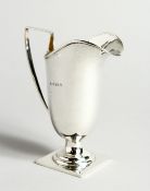 A HELMET-SHAPED SILVER CREAM JUG on a square base. Birmingham 1908. 12cm tall - 78g