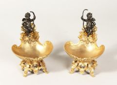 A PAIR OF ORMOLU AND BRONZE CUPID SALTS 7ins high.
