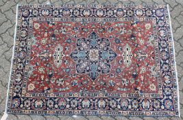 AN EARLY 20TH CENTURY PERSIAN RUG, claret ground with stylised decoration, within a blue ground
