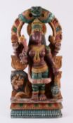 AN INDIAN CARVED WOOD & POLYCHOME FIGURE OF DURGA, depicted with a comical faced lion, four arms