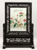 A CHINESE PORCELAIN SCREEN, with flowers and calligraphy, 14ins x 9.5ins on a wooden stand.