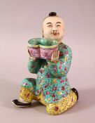 A CHINESE FAMILLE ROSE TURQUOISE GROUND PORCELAIN FIGURE OF A BOY, the boy knelt holding a basket,