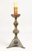 AN EARLY ORIENTAL CHAMPLEVE ENAMEL CANDLESTICK, 12ins high.