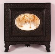 A GOOD INDIAN CARVED EBONY & PAINTED frame, the frame carved with native foliage, the centre with