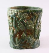A CHINESE GREEN HARDSTONE BRUSH POT, carved with figures and trees, calligraphy, 15.5cm high.